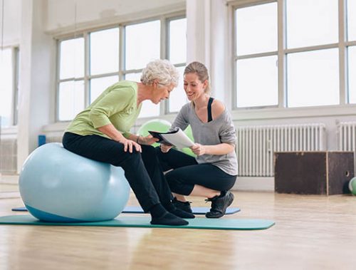 Trainer reviewing exercise plan with senior woman