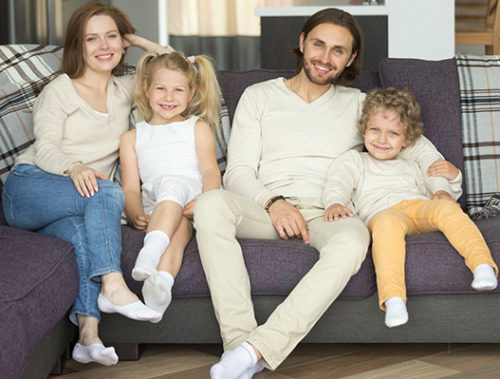 Smiling family of four sitting on couch